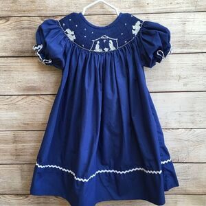 SMOCKED A LOT SMOCKED DRESS WITH EMBROIDERED NATIVITY SCENE